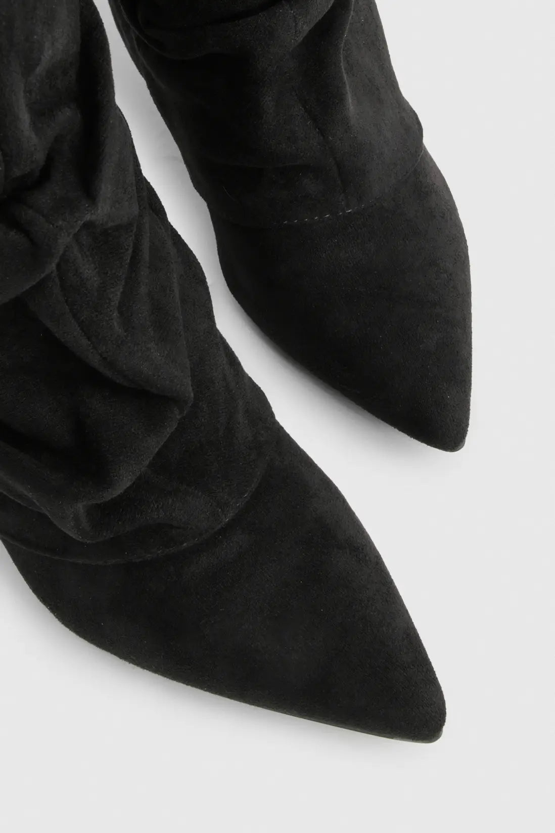 Close-up of a black suede slouchy knee-high boot showing the pointed toe.