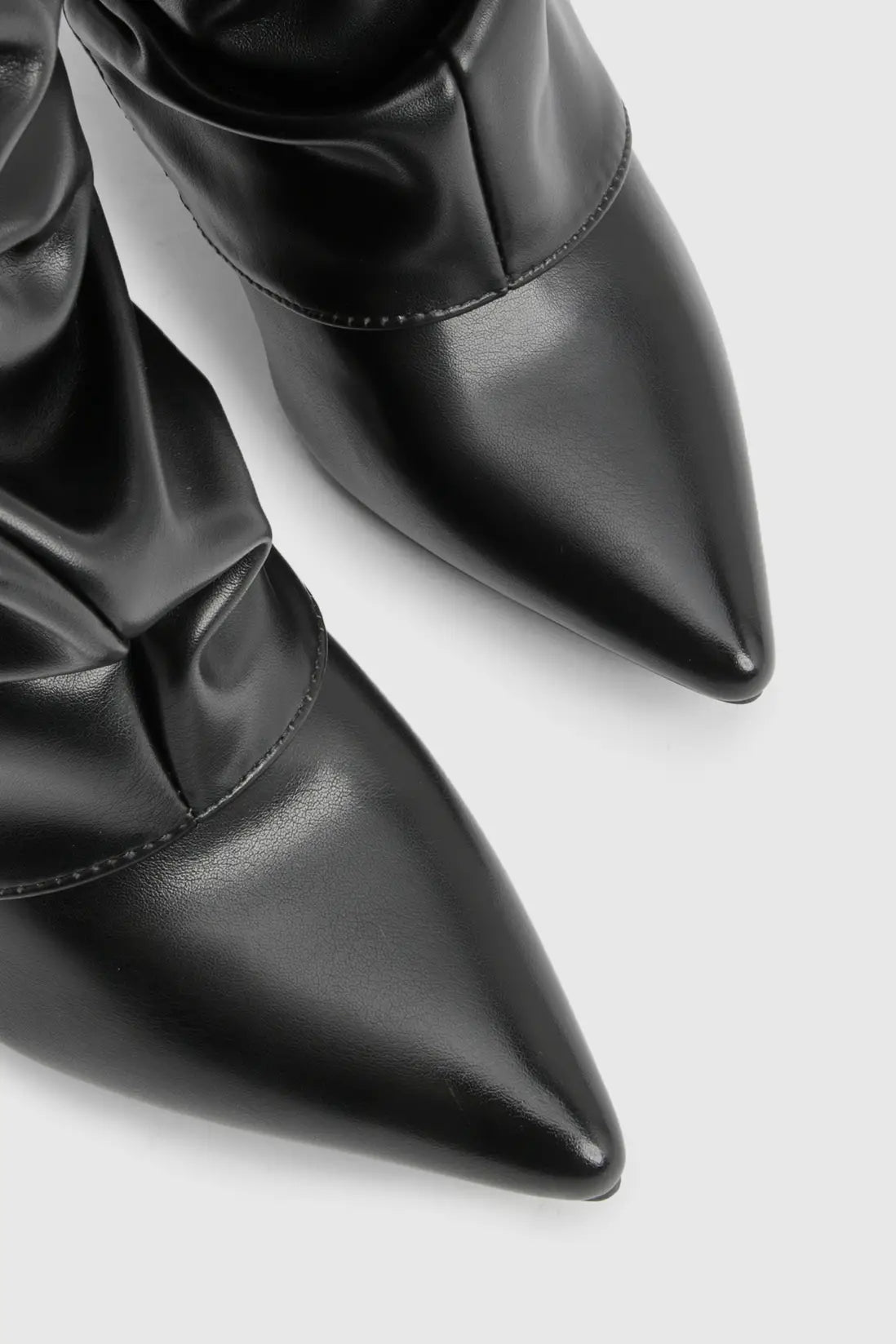 Close-up of a black leather pointed-toe knee-high boot with a smooth finish.