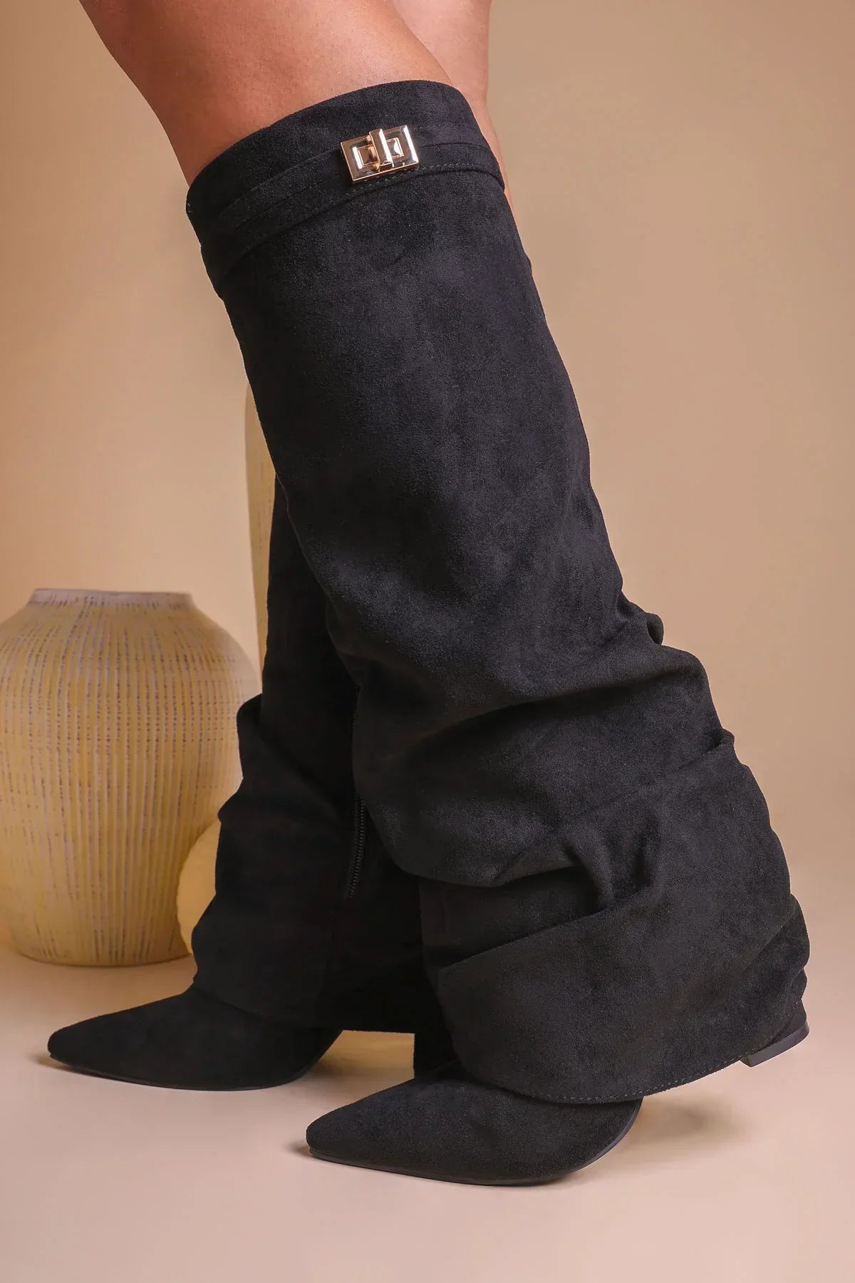 Black suede slouchy knee-high boots worn with a short outfit.