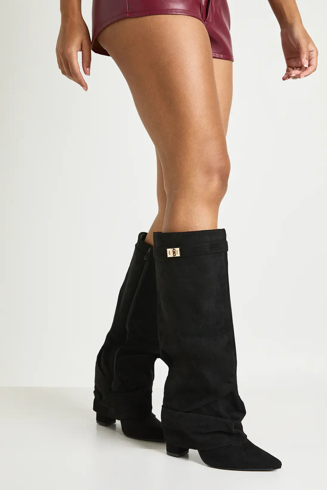Woman wearing black suede slouchy knee-high boots with a burgundy skirt.