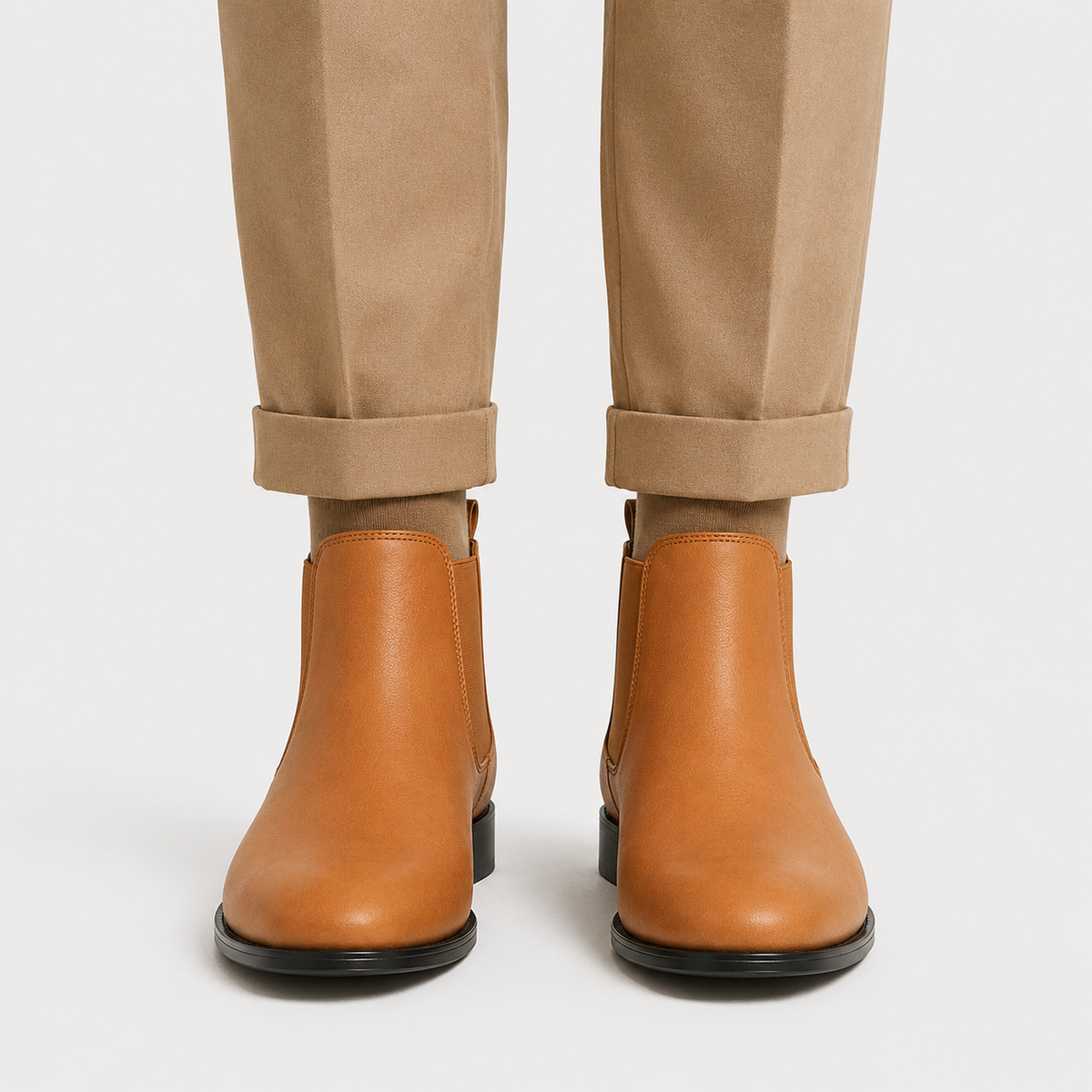 Brown leather Chelsea boots with elastic side panels, round toe, and low block heel worn with cuffed khaki trousers.