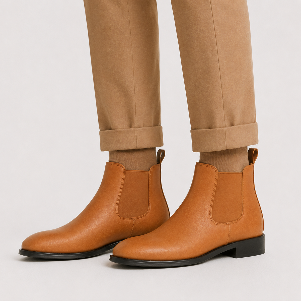 Brownleather Chelsea boots with elastic side panels, round toe, and low block heel worn with cuffed tan trousers.