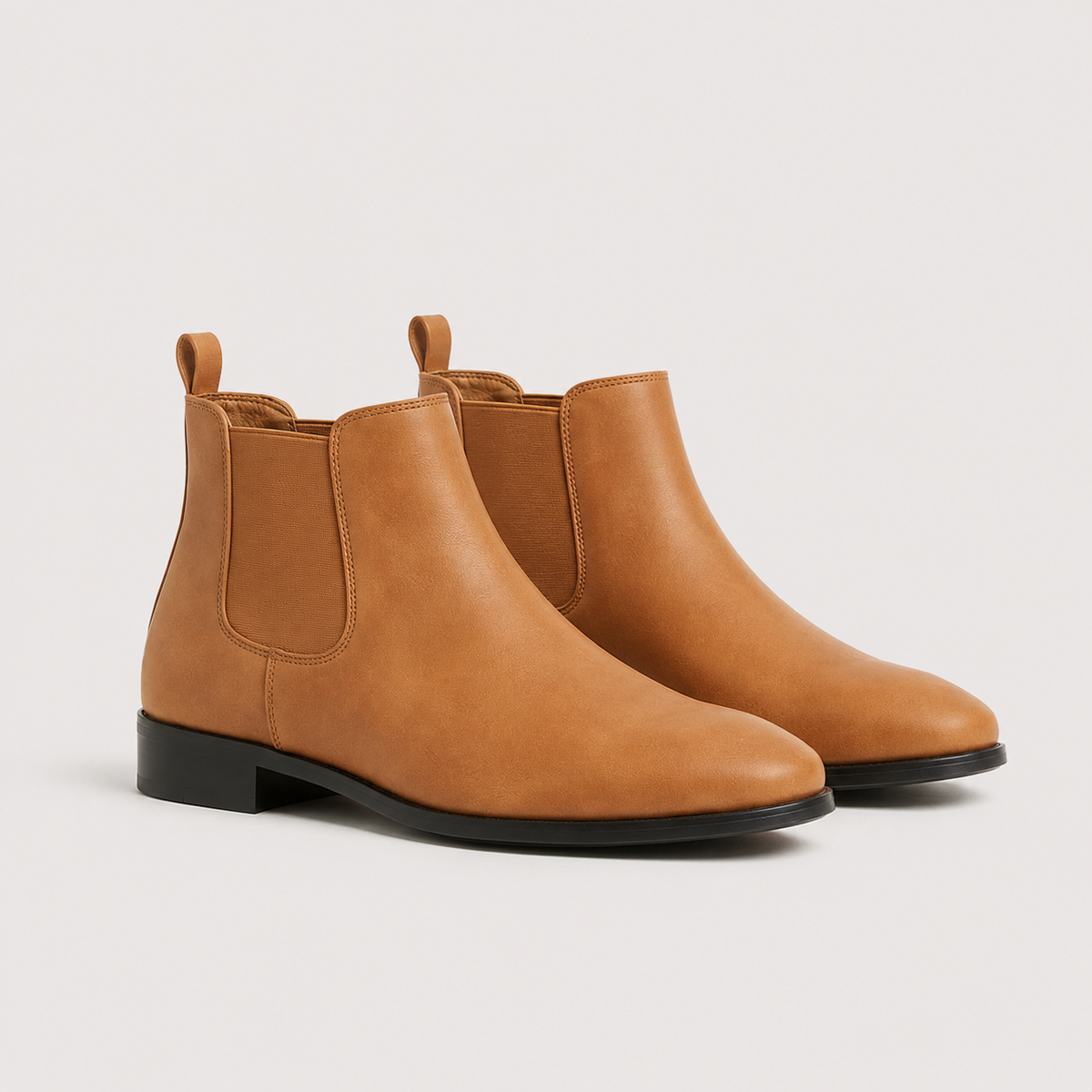 Brown leather Chelsea boots with elastic side panels, rounded toes, and low black block heels on a neutral background.