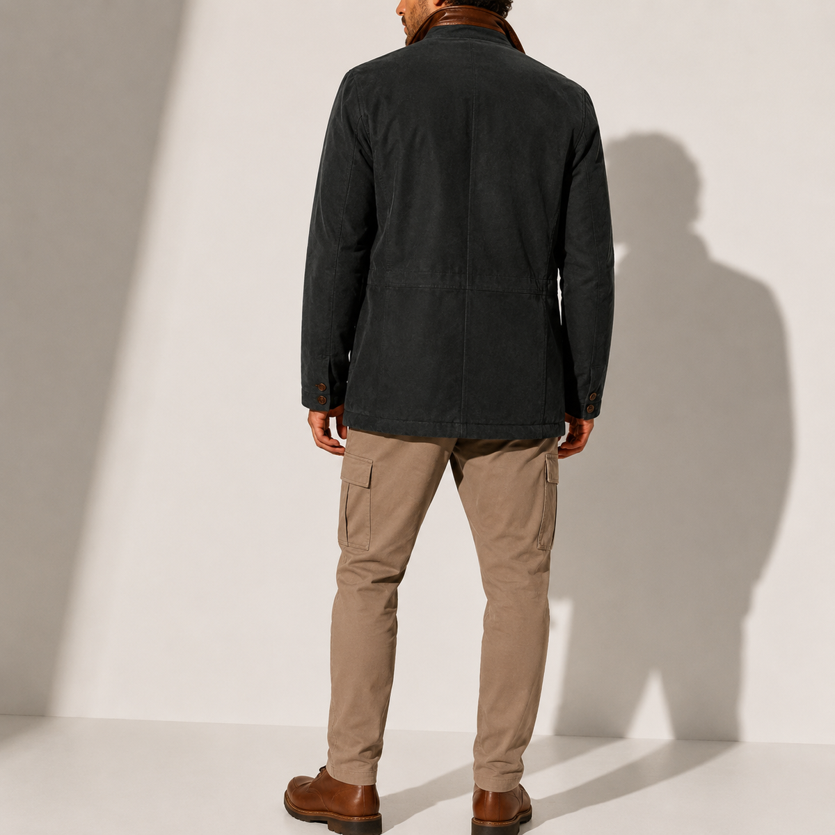 A man wearing a black suede blazer jacket with a stand collar, tailored fit, and button front, back view
