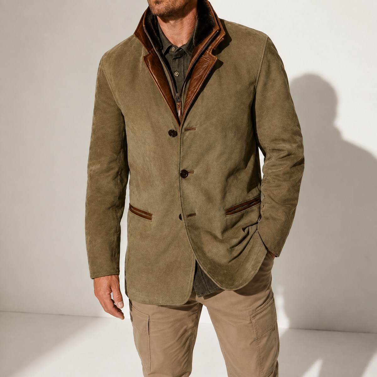 A man wearing an olive brown suede blazer jacket with a stand collar, tailored fit, button front, and contrast trim