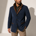 A man wearing a navy blue suede blazer jacket with a stand collar, tailored fit, button front, and contrast trim