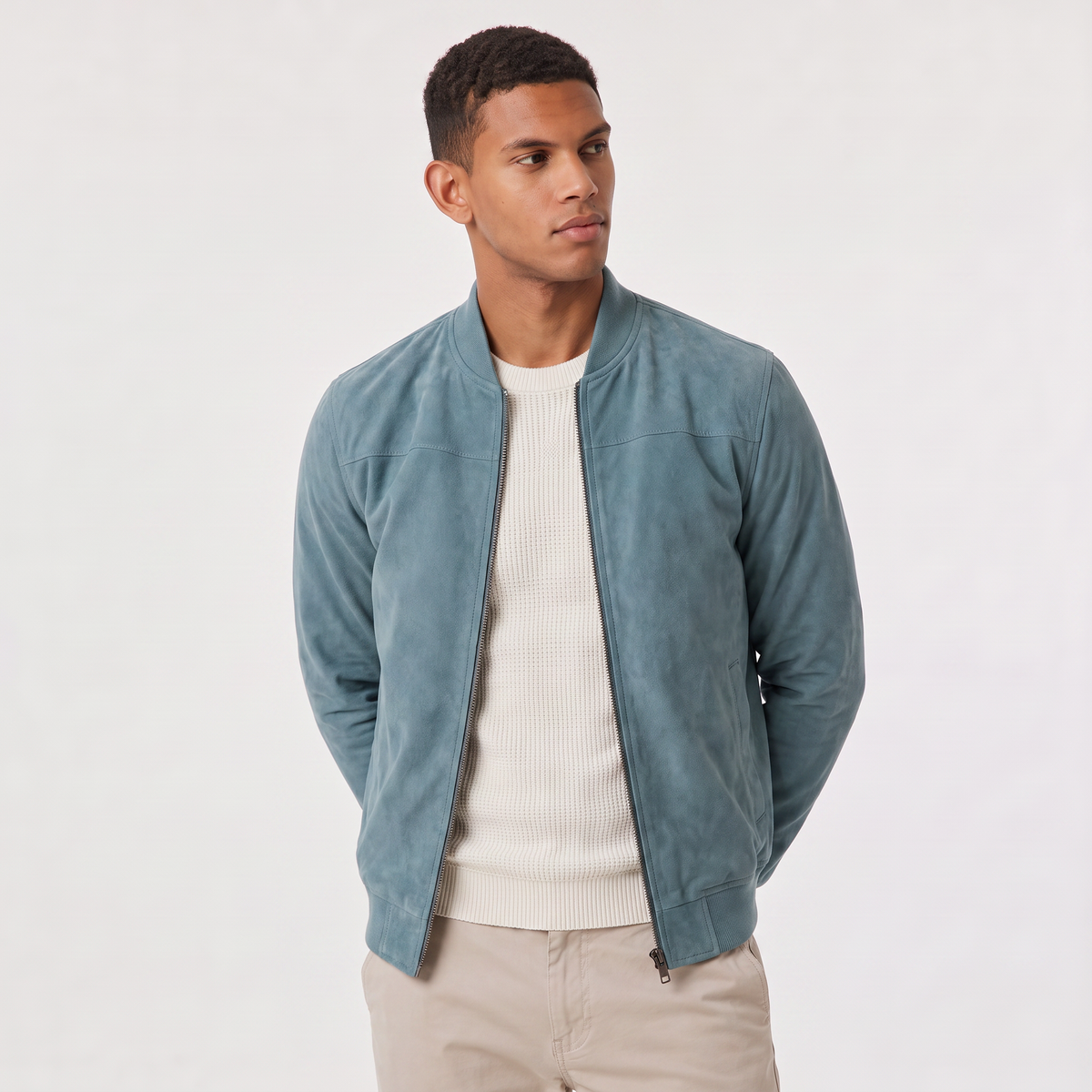 A man wearing a light blue suede bomber jacket with a zip-up front, stand collar, and ribbed cuffs