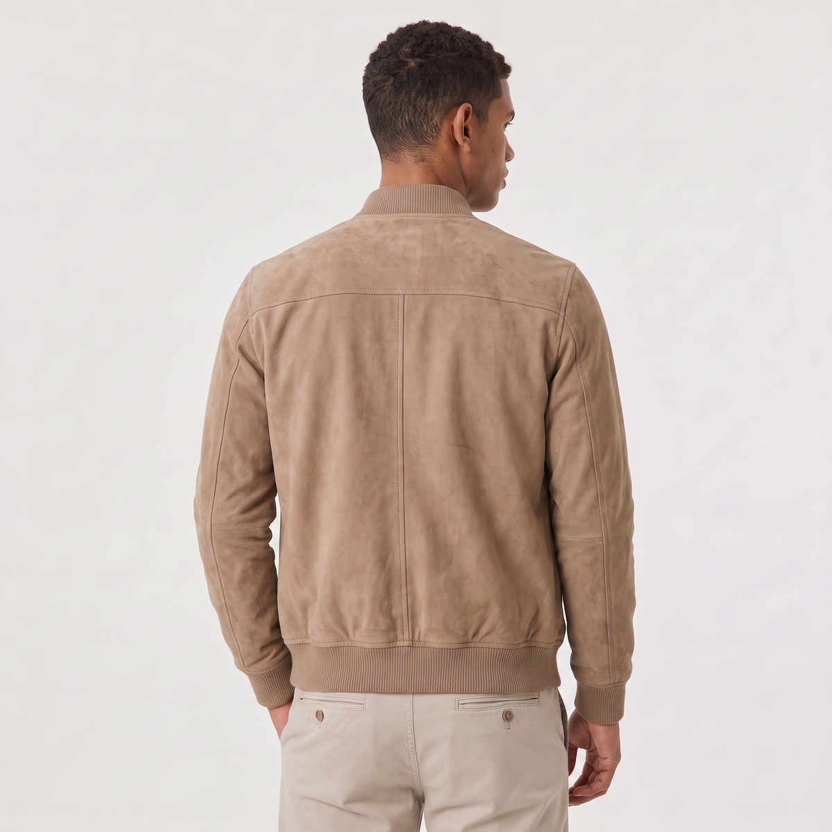 A man wearing a brown suede bomber jacket with a zip-up front and stand collar, back view