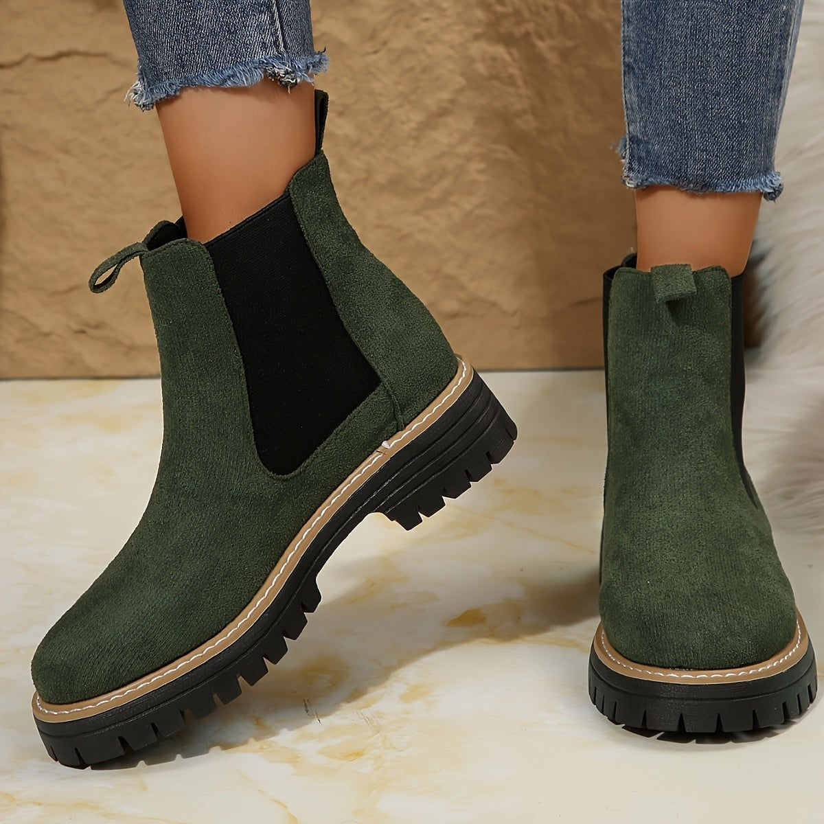 Green suede Chelsea ankle boots for women with black elastic gussets and lug sole, worn with cropped jeans