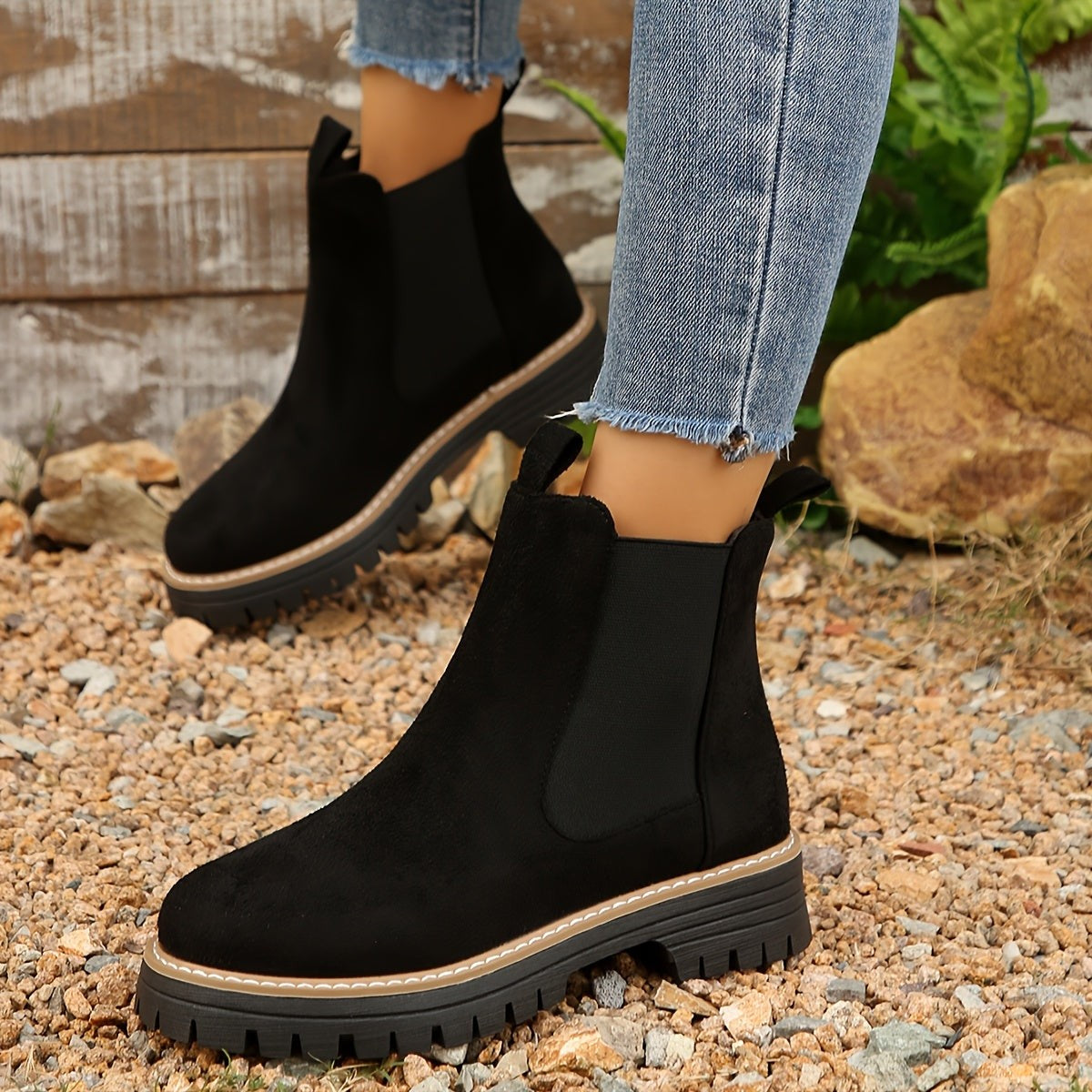 Black suede lug sole Chelsea ankle boots for women shown from the side, with contrast stitched welt