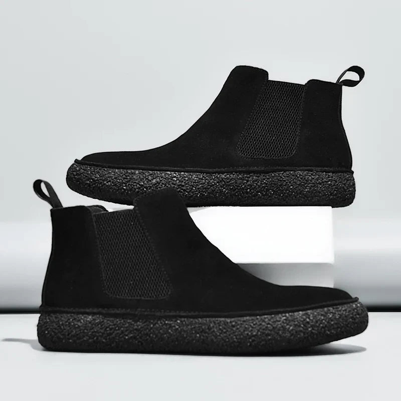 Pair of black Chelsea boots displayed together, featuring elastic side panels, pull tabs, and thick textured soles.