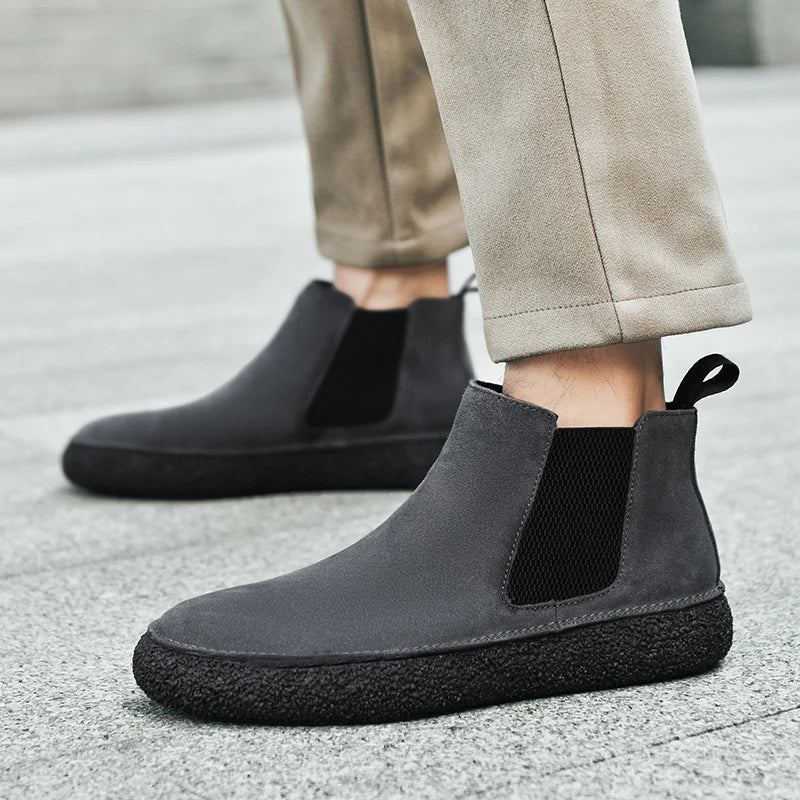 Person wearing black Chelsea boots with light trousers, showing the side profile and sole.
