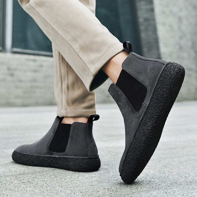 Person wearing black Chelsea boots while walking outdoors, highlighting the elastic panels and chunky soles.