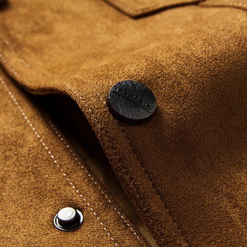 Close-up of tan suede jacket fabric showing a button closure, stitching, and textured suede surface