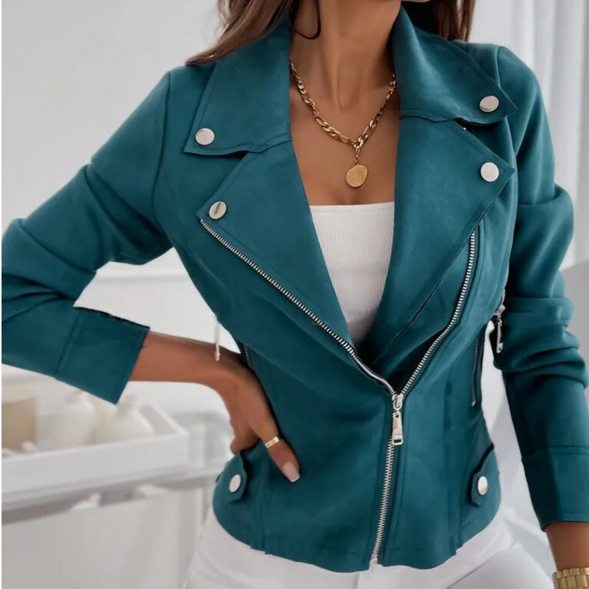 A woman wearing a dark teal suede jacket with an asymmetrical zip, notched lapel, and hip-length fit