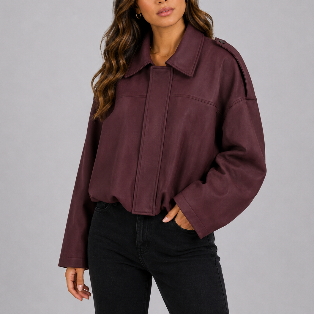 A woman wearing a burgundy suede jacket with an oversized fit, bomber style, and wide sleeves