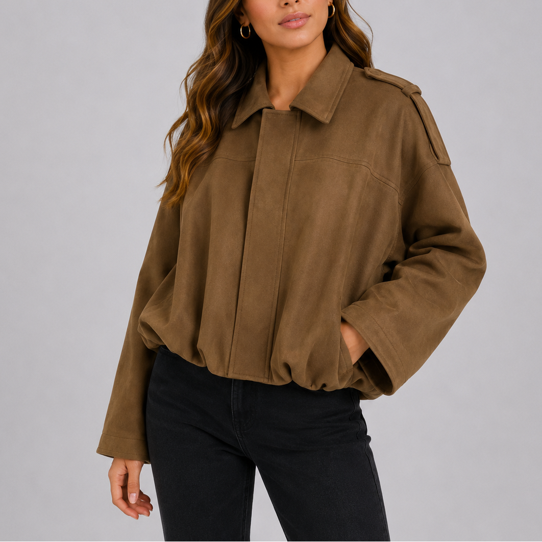 A woman wearing a tan suede jacket with an oversized fit, bomber style, and wide sleeves