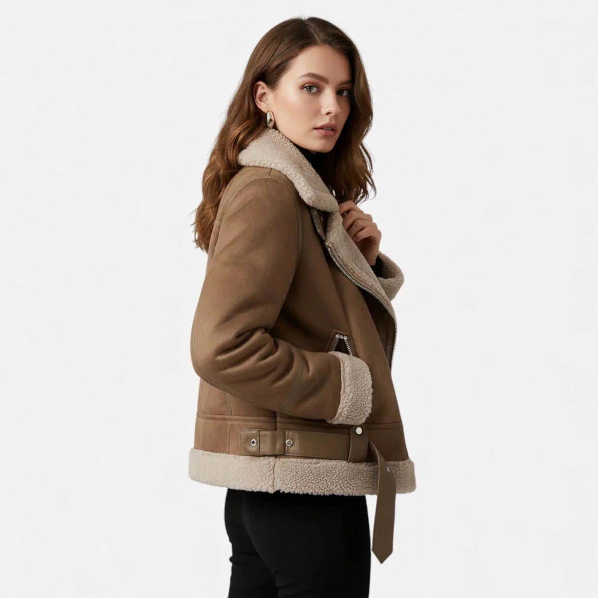 A woman wearing a brown suede shearling aviator jacket with a belted waist, asymmetric zip front, and plush shearling collar