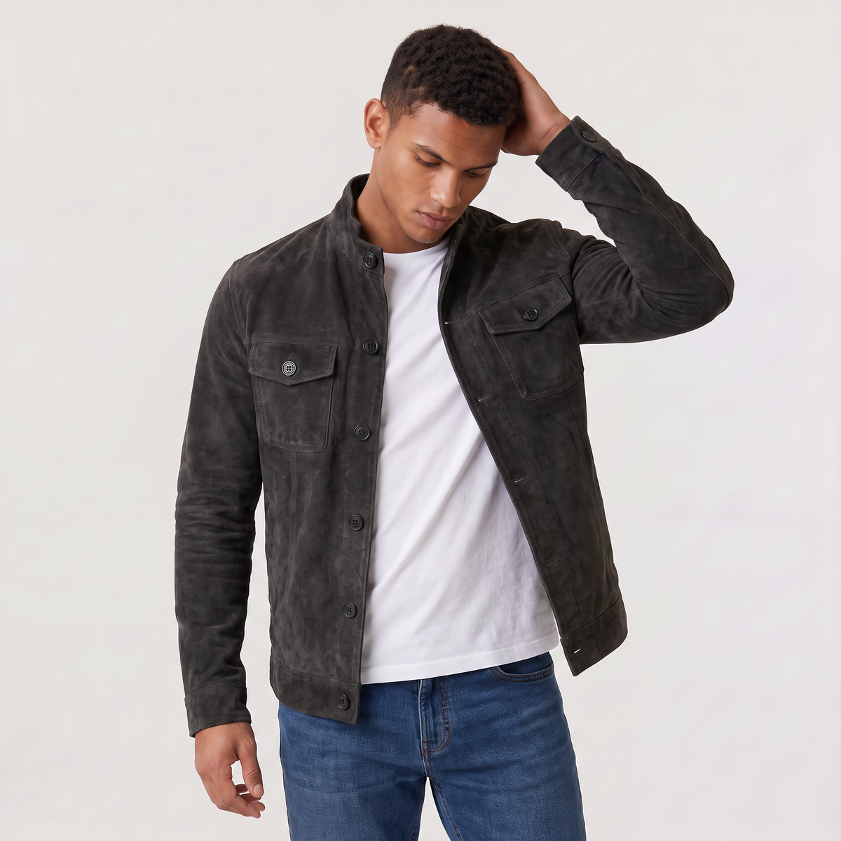 A man wearing a dark brown suede trucker jacket with a button front, stand collar, and chest pockets