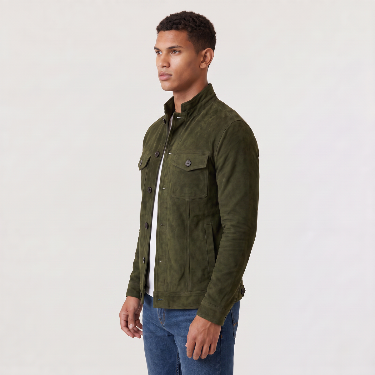A man wearing an olive green suede trucker jacket with a button front, stand collar, and chest pockets, side view