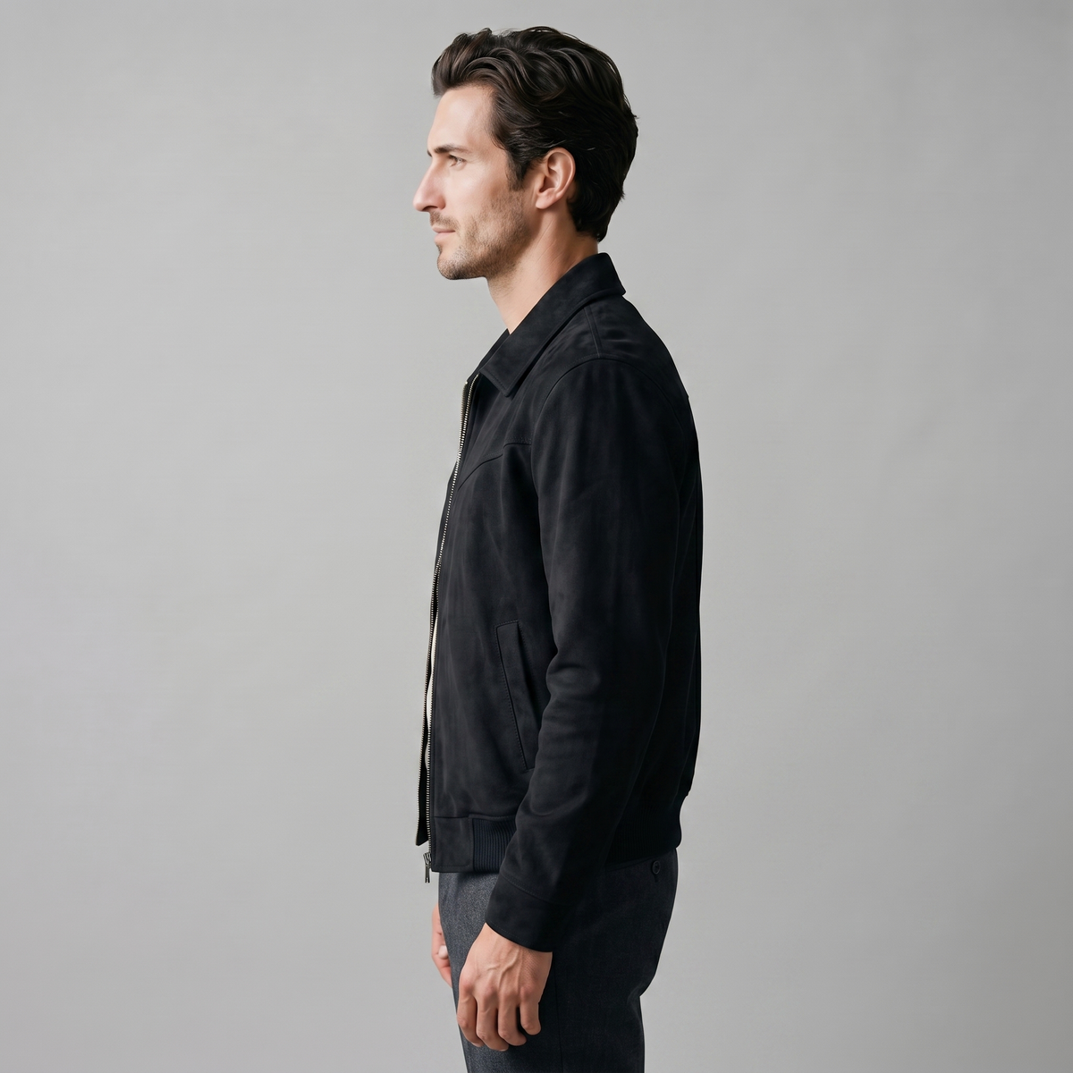 A man wearing a black suede trucker jacket with a button front, stand collar, and chest pockets, side view