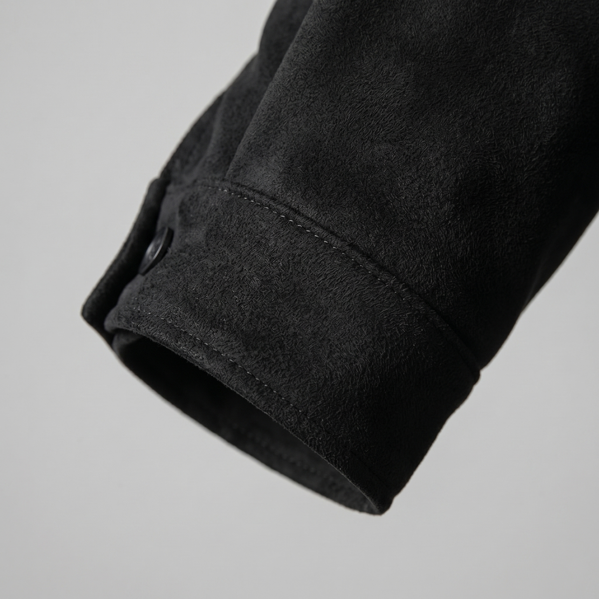 Close-up of a black suede trucker jacket sleeve showing the cuff and suede texture