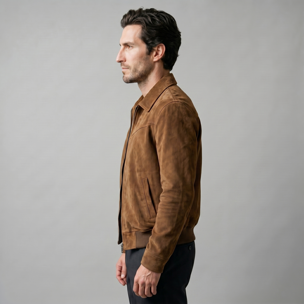 A man wearing a brown suede trucker jacket with a button front, stand collar, and chest pockets, side view