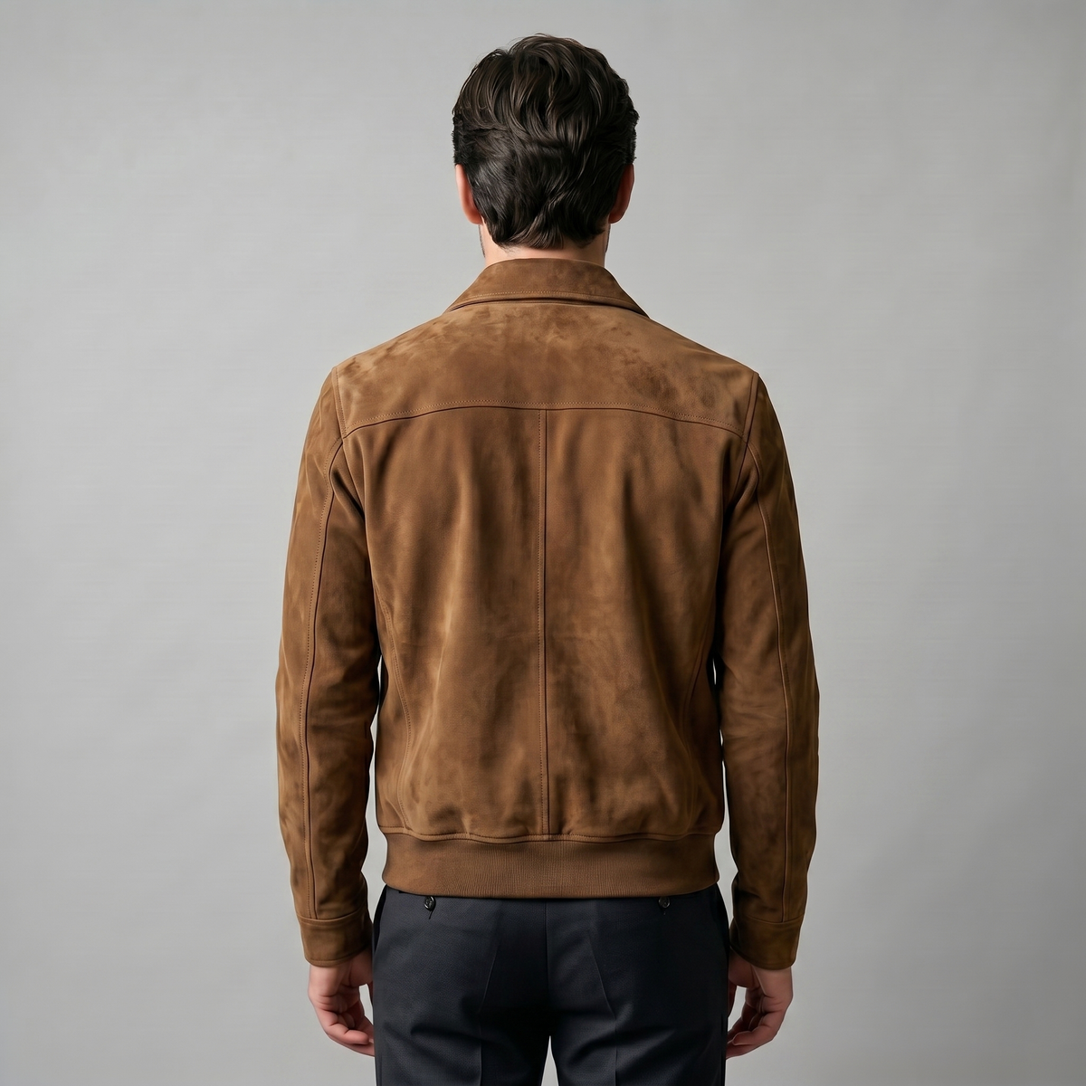 A man wearing a brown suede trucker jacket with a button front, stand collar, and chest pockets, back view