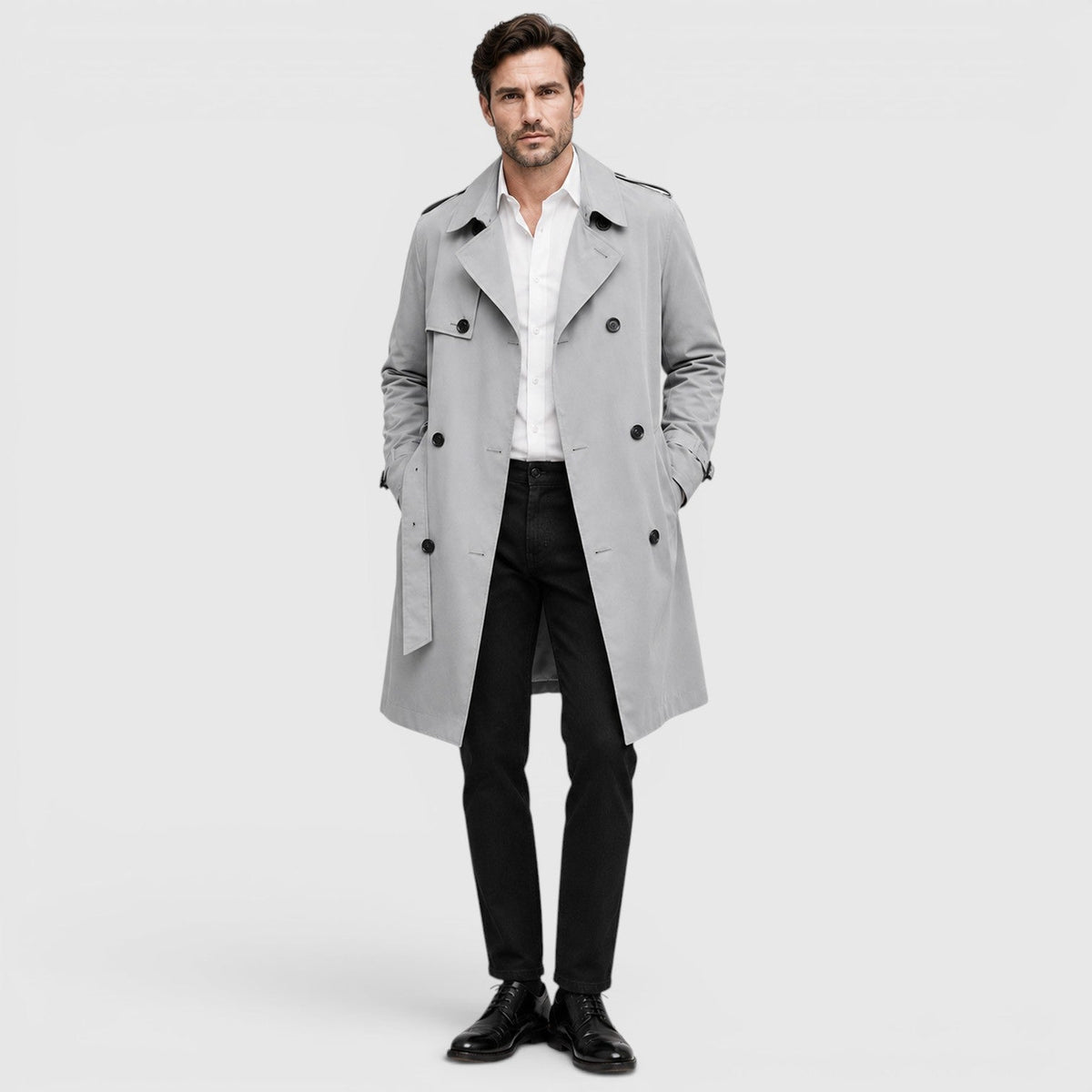 A man wearing a light gray tailored double-breasted trench coat with an adjustable belt and notch lapel, front view