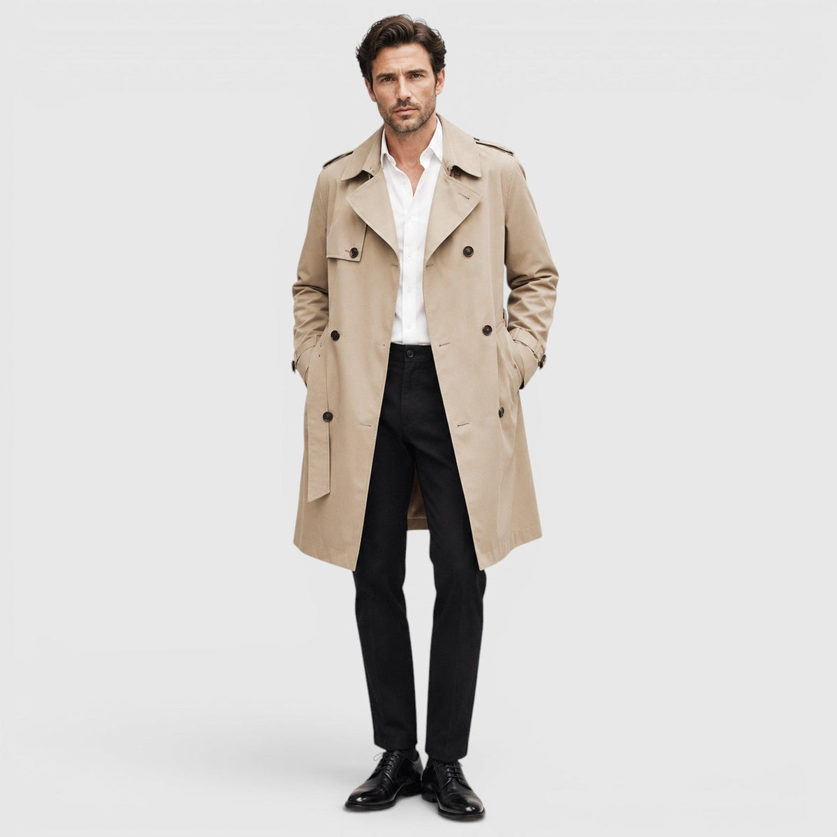 A man wearing a beige tailored double-breasted trench coat with an adjustable belt and notch lapel, shown in side view