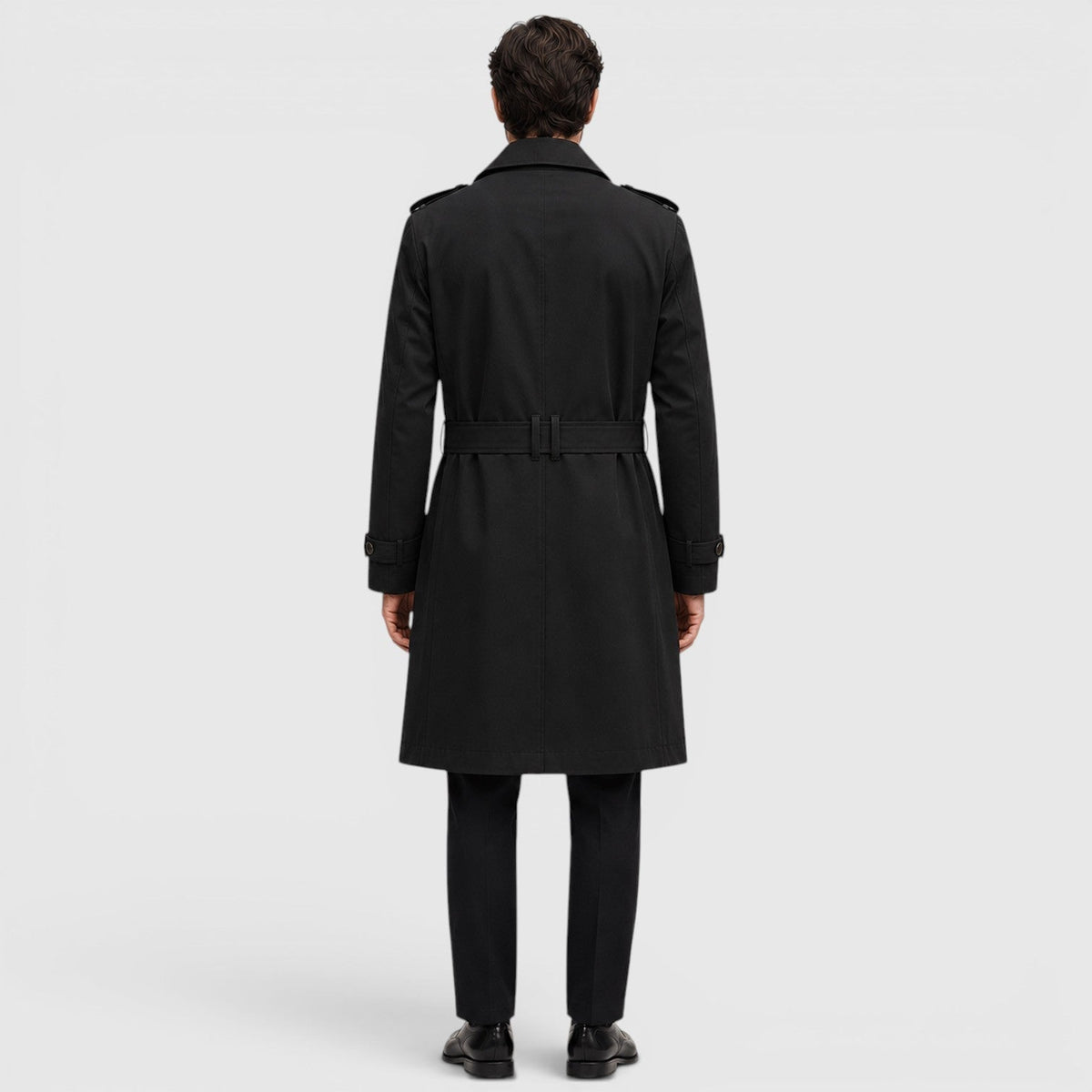 A man wearing a black tailored double-breasted trench coat with an adjustable belt, shown from the back