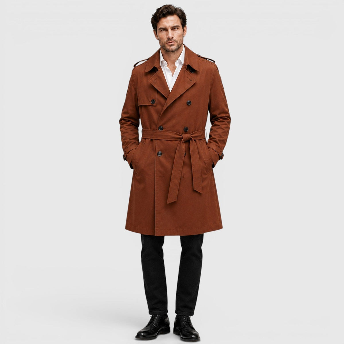 A man wearing a rust brown tailored double-breasted trench coat with an adjustable belt and notch lapel