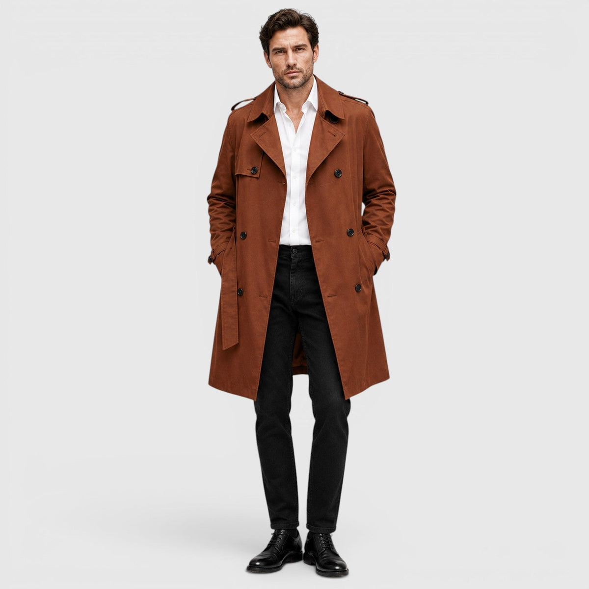 A man wearing a rust brown tailored double-breasted trench coat with an adjustable belt and notch lapel, shown in side view