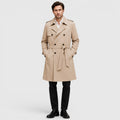A man wearing a beige tailored double-breasted trench coat with an adjustable belt and notch lapel