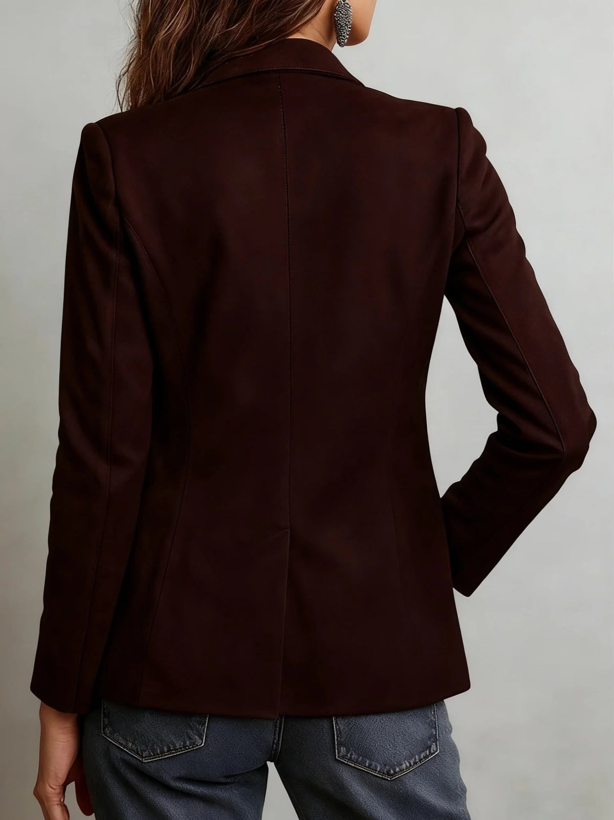 A woman wearing a dark brown tailored suede blazer, shown from the back with patch pockets and a tailored fit