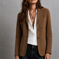 A woman wearing a brown tailored suede blazer with patch pockets and a notch lapel