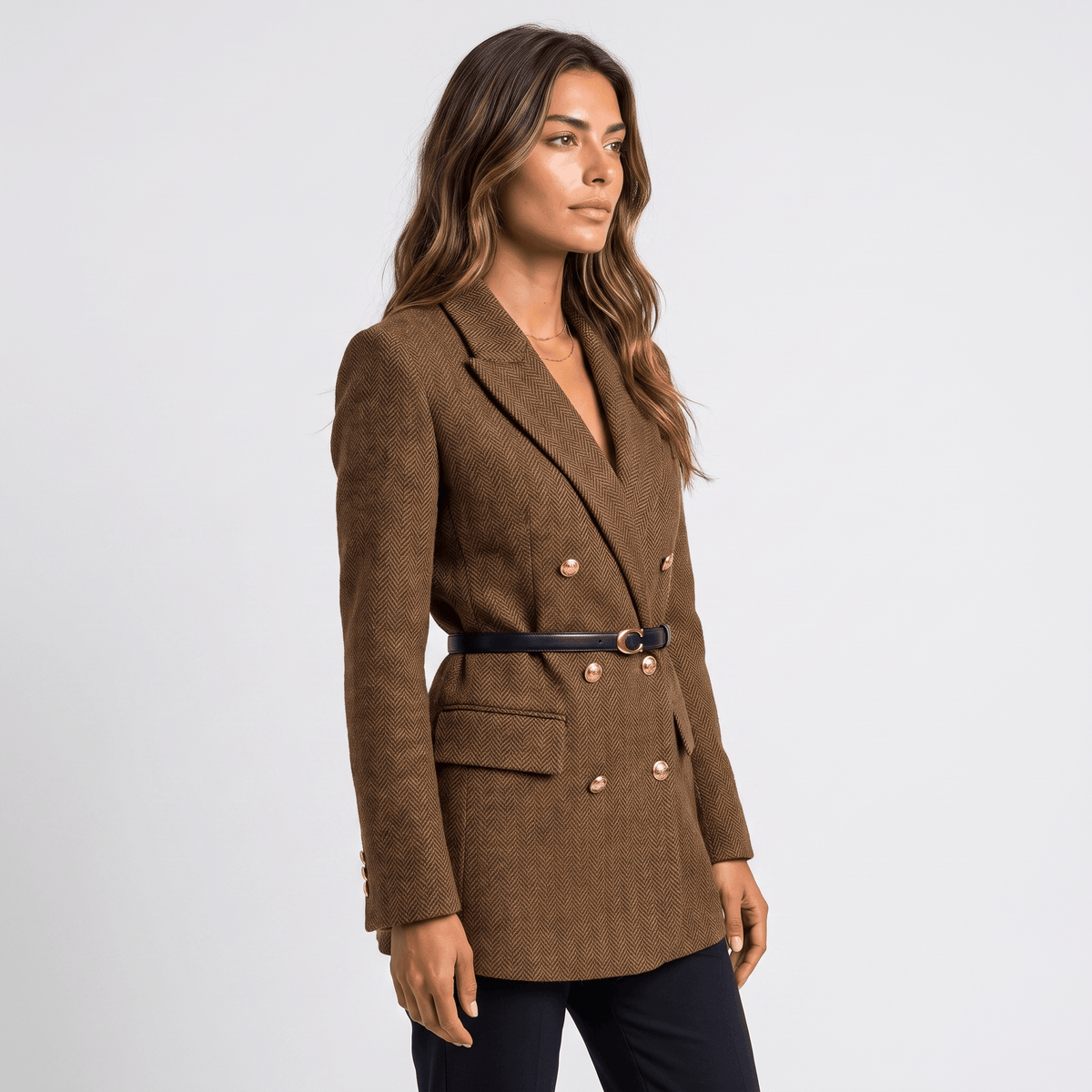 Side view of a woman wearing a brown double-breasted tweed blazer with a belted waist, notched lapels, and tailored fit