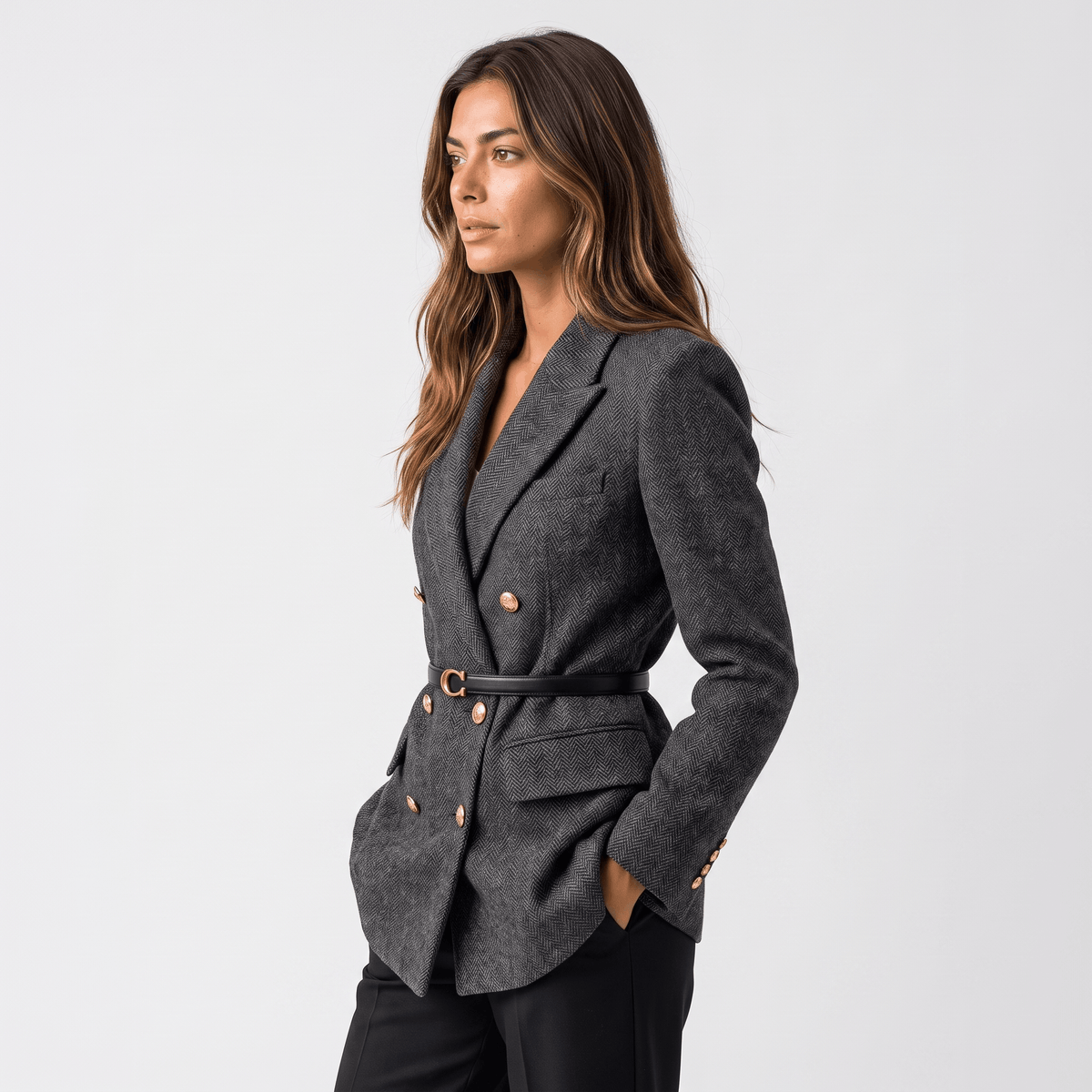 Side view of a woman wearing a charcoal gray double-breasted tweed blazer with a belted waist and tailored silhouette.
