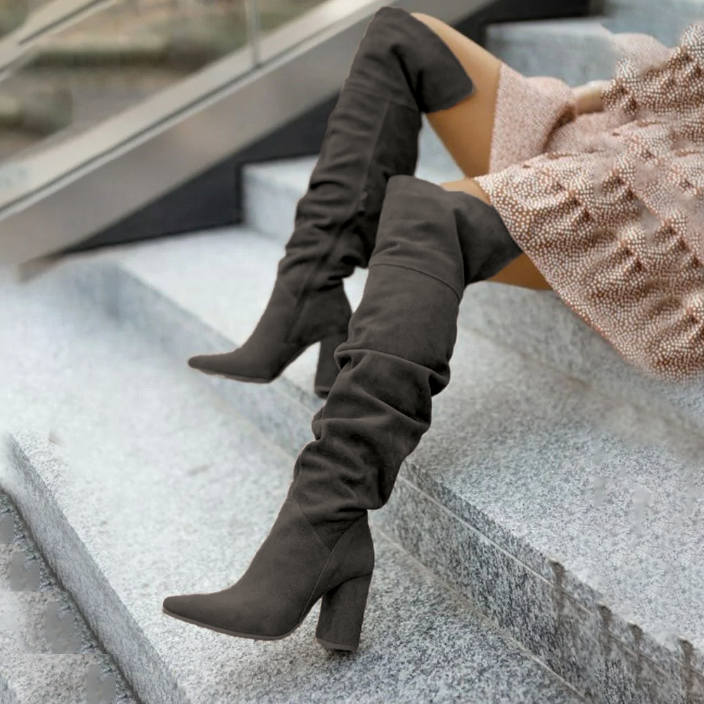 Dark Gray suede thigh-high boots with a pointed toe, slouchy shaft, and stacked block heel, worn on stone steps.