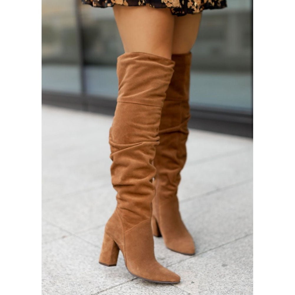 Brown suede thigh-high boots with a pointed toe, stacked block heel, and a relaxed, gathered slouch shaft.