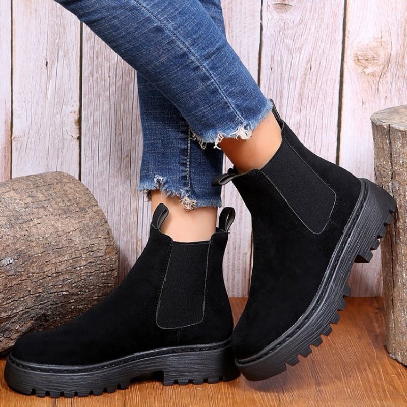 Black vegan leather platform Chelsea ankle boots for women with cleated lug sole, worn with cropped jeans