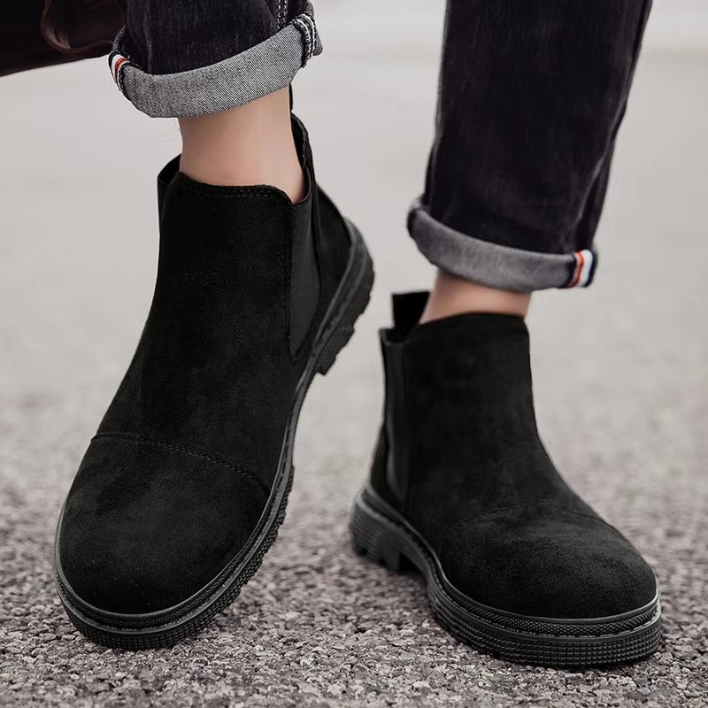 Black vegan suede Chelsea boots for men with lug sole, worn with cuffed black jeans on pavement