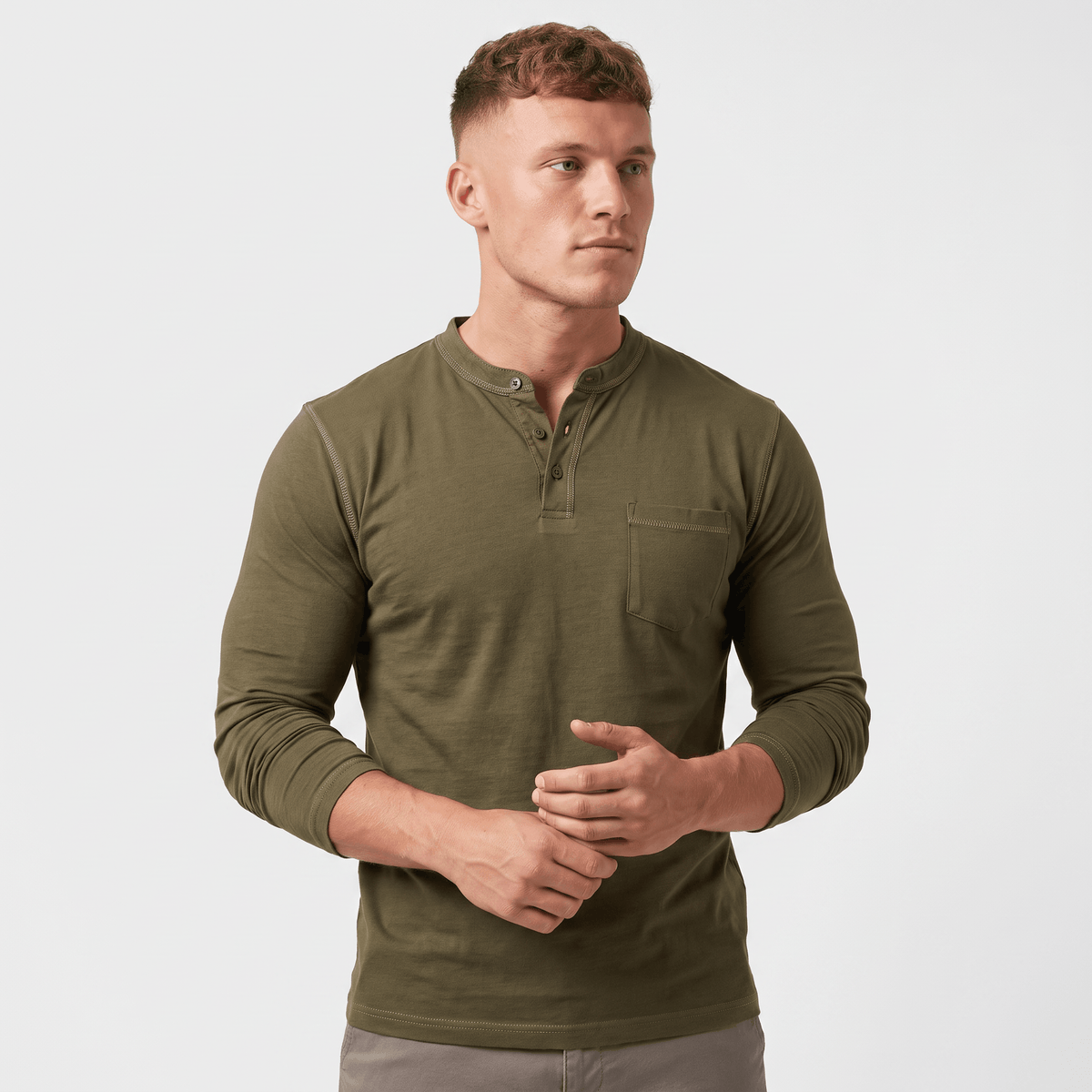 Side view of a man wearing an olive green long-sleeve Henley shirt featuring a three-button neckline, chest pocket, and tailored silhouette.