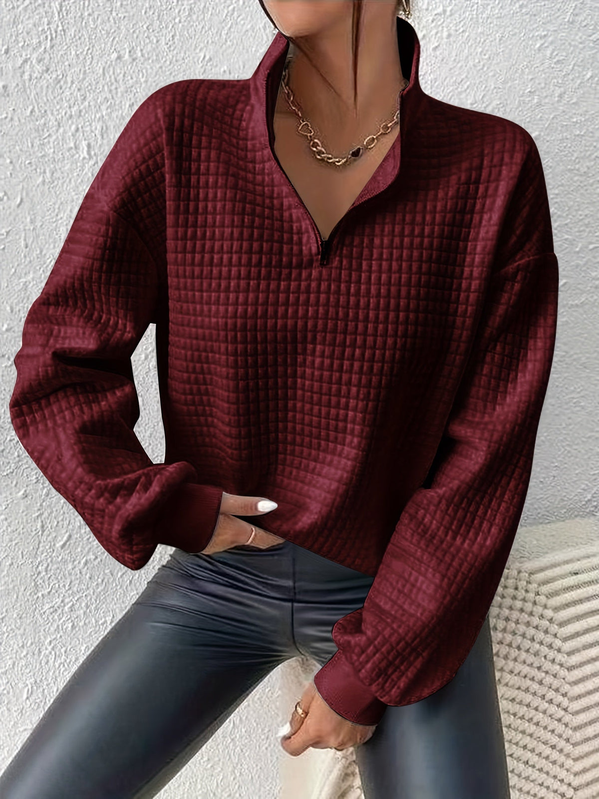 Burgundy waffle knit quarter-zip sweater worn by a female model, front view