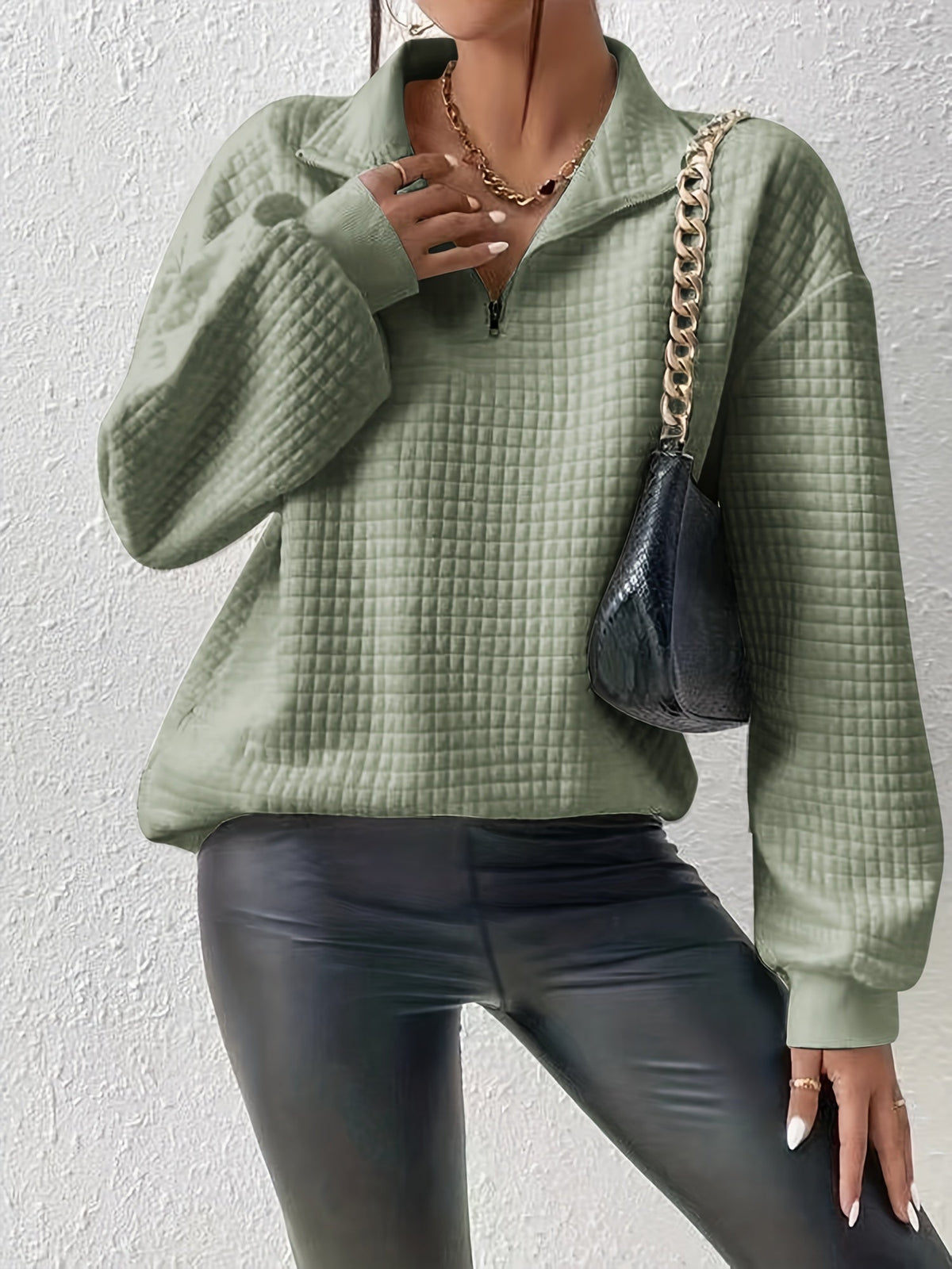 Green waffle knit quarter-zip sweater worn by a female model with a shoulder bag