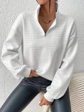 White waffle knit quarter-zip sweater with long sleeves, ribbed cuffs, and textured waffle knit fabric