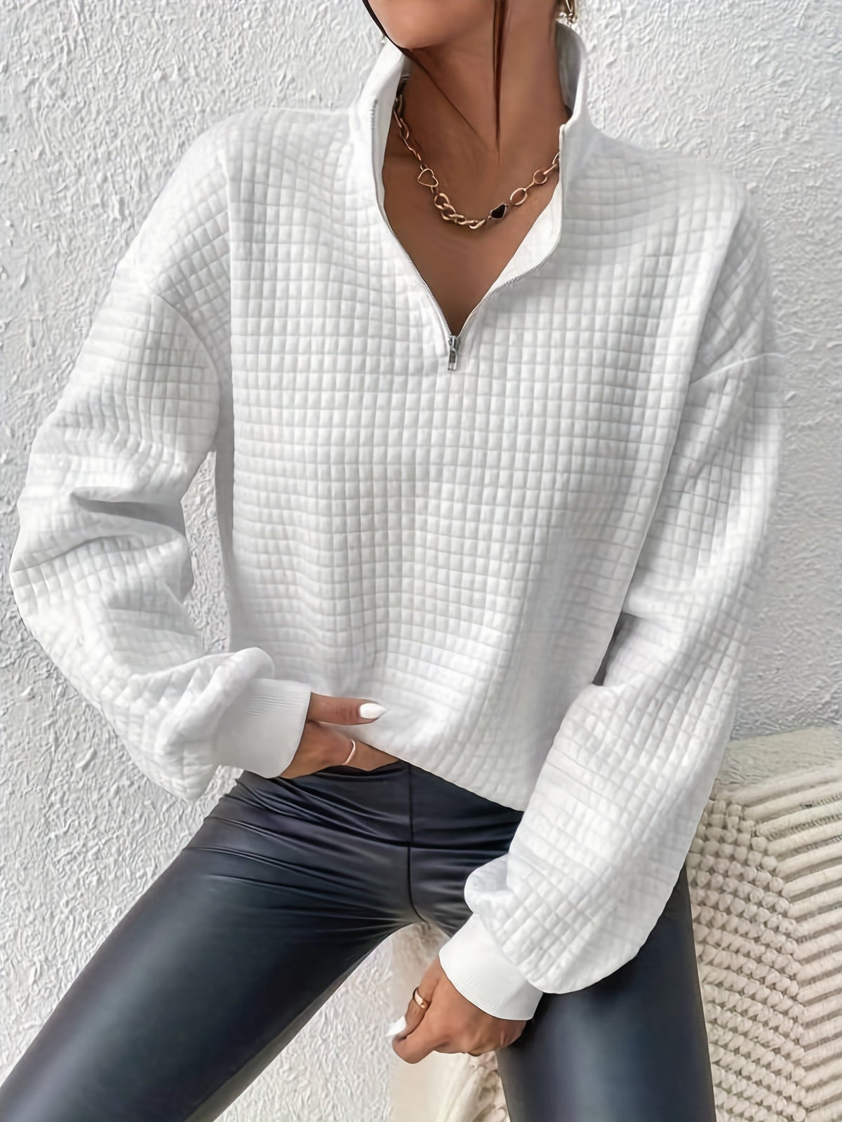 White waffle knit quarter-zip sweater with long sleeves, ribbed cuffs, and textured waffle knit fabric