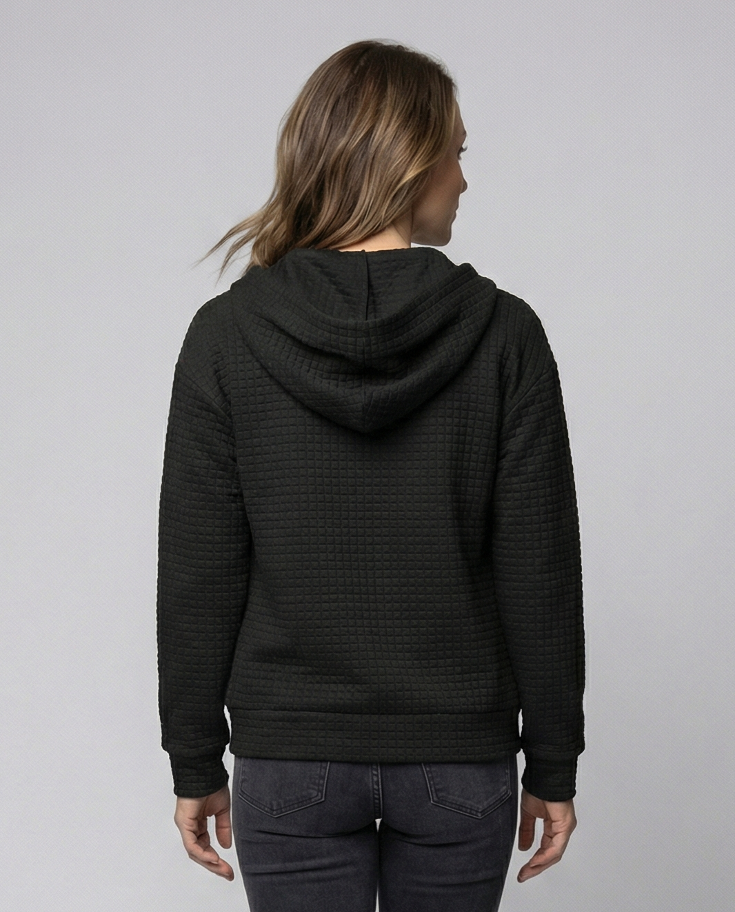 Black fitted waffle knit zip-up hoodie for women shown from the back with a drawstring hood