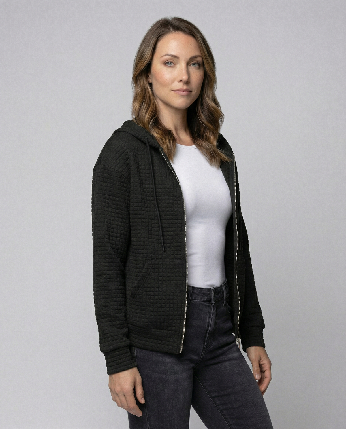 Black fitted waffle knit zip-up hoodie for women worn by a female model, front view