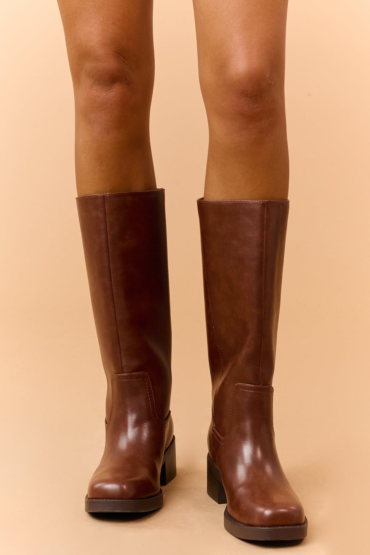 Front view of brown knee-high boots worn on both legs.